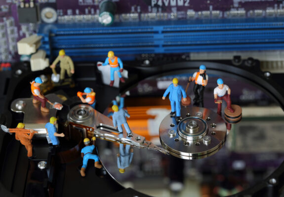 Selective focus of miniature engineer and worker maintenance and fixed problem harddisk of Personal computer (PC) on blurred mainboard background as business and industrial concept.